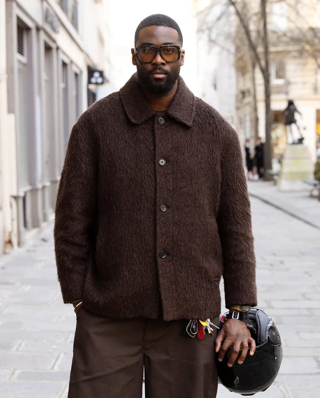 A monochrome brown street-style look with a fuzzy button-front jacket, wide trousers, and oversized tinted sunglasses.