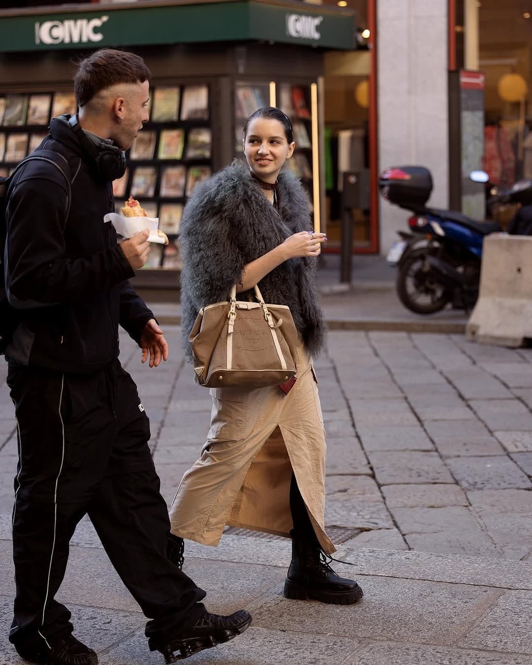 A grey shaggy faux-fur jacket is styled over a beige wrap maxi skirt with black lace-up platform boots and a tan Prada handbag.